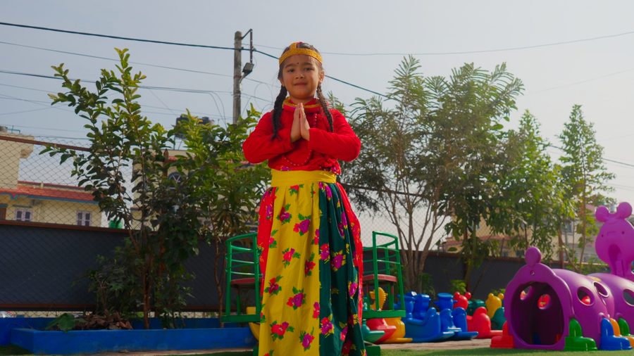 A child in traditional Nepali dress performing at a school event