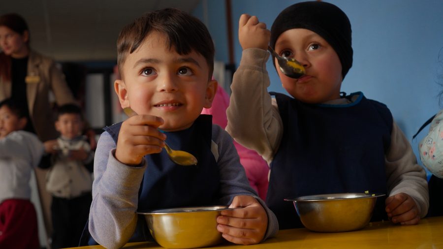 Two children eating lunch from steel bowls at school