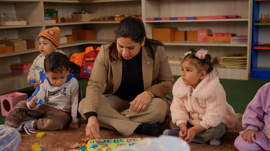 A teacher reading with a small group of children seated on the floor