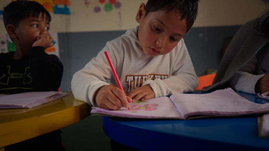 A primary-age boy writing in an exercise book